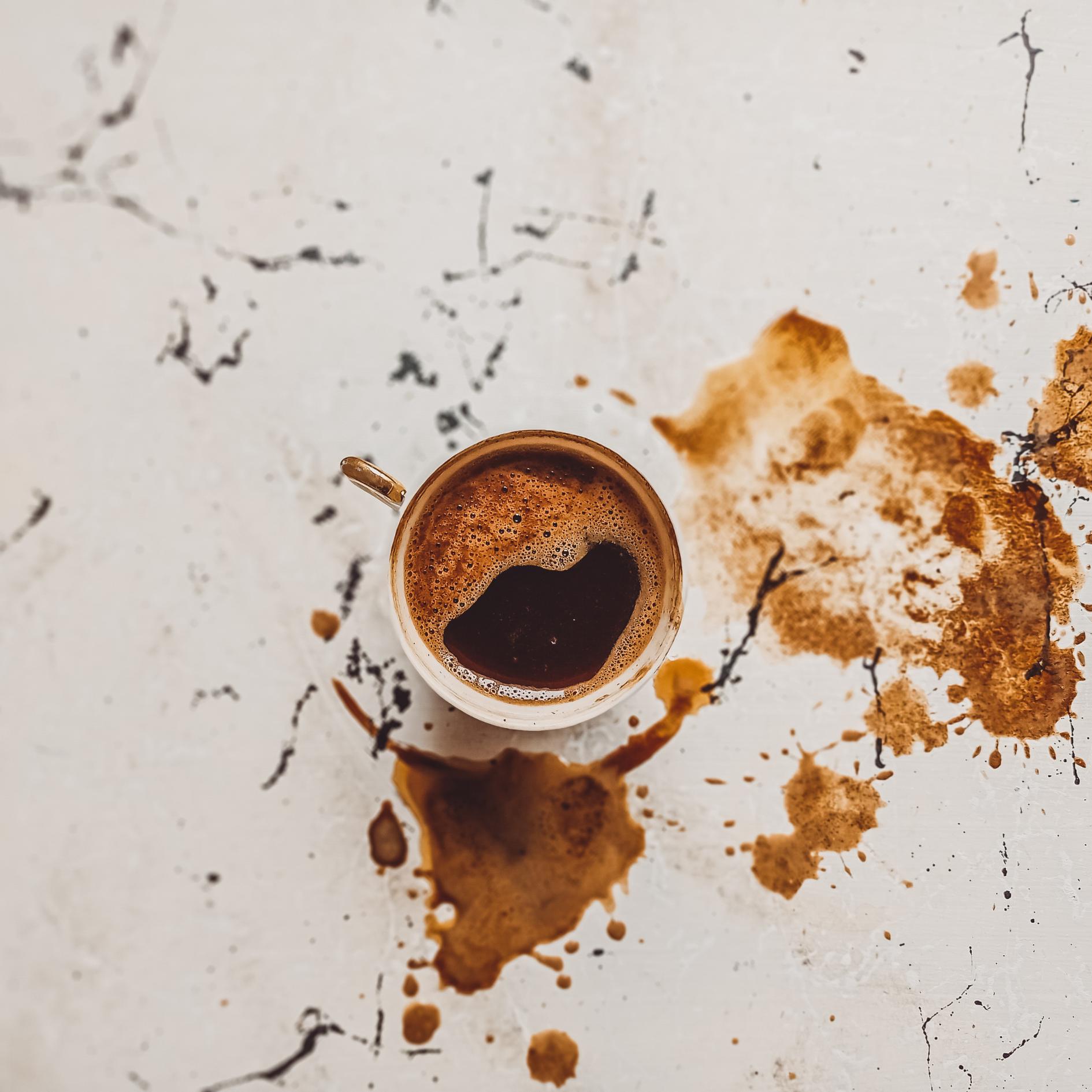 Coffee cup with coffee spill on a textured surface