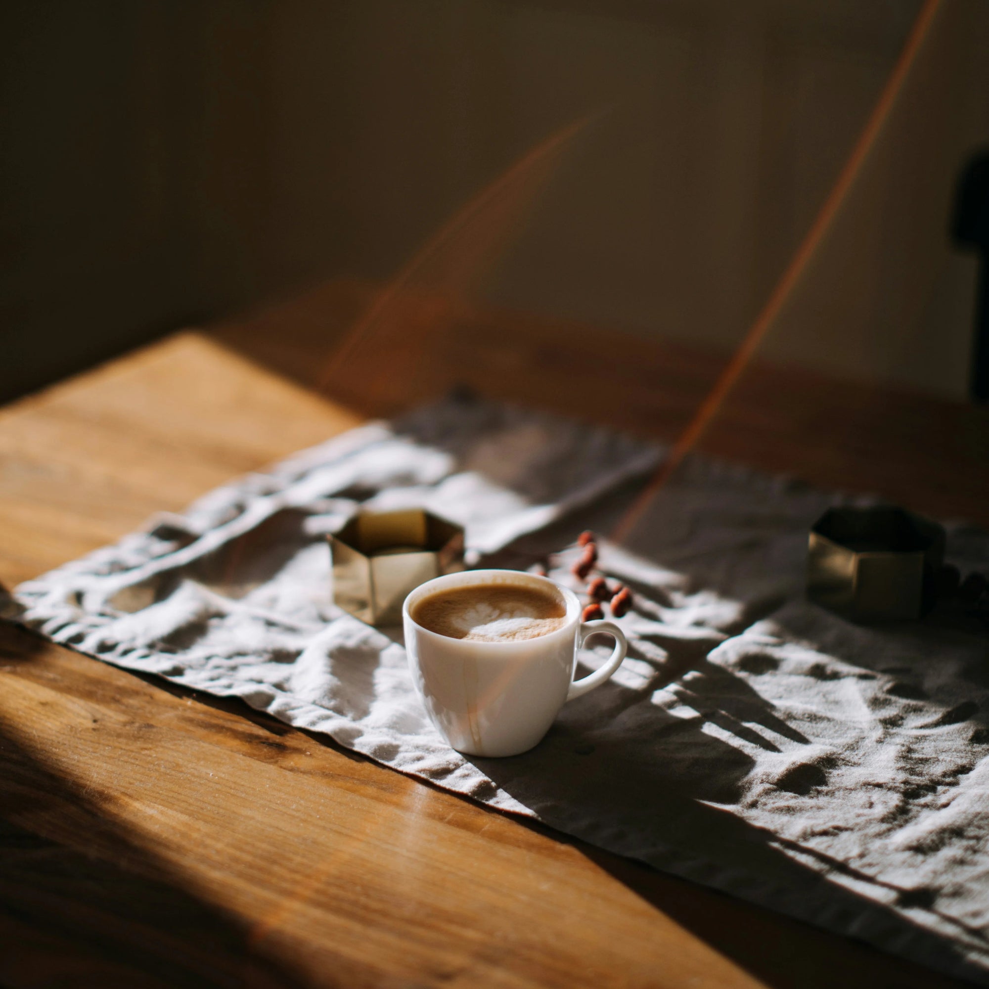 Cup of coffee on a textured mat with a warm glow on a wooden surface